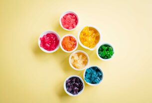 Colorful cannabis gummy edibles in white bowls arranged on a yellow background