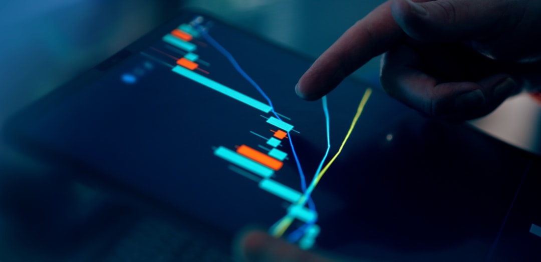 Finger pointing at a digital chart on a tablet showing financial trends and fluctuations.